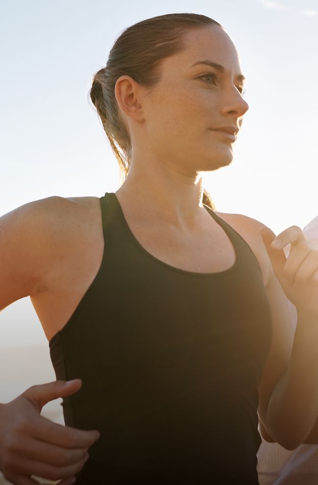 HBOT model jogging in sunlight, focused expression.